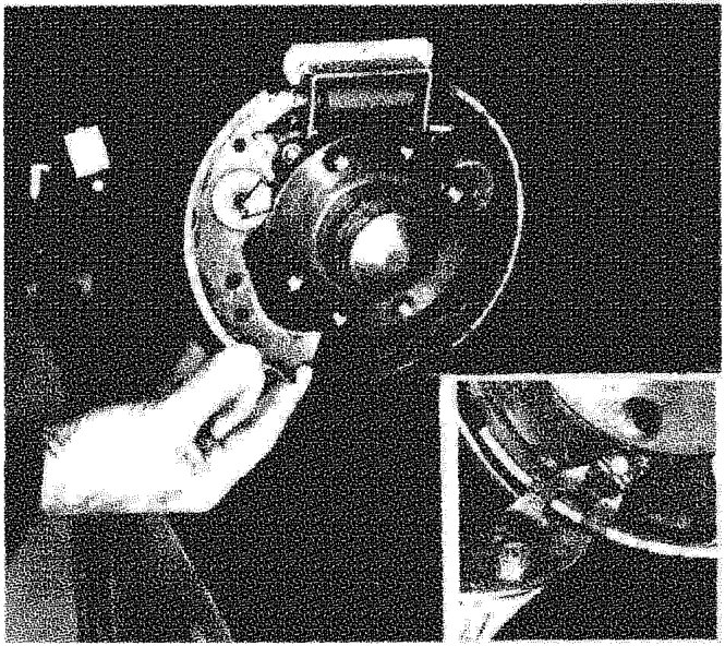 A hand holding a brake shoe against a brake disc and hub assembly.