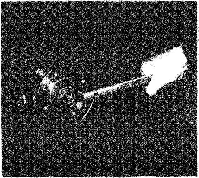A hand using a wrench to remove a nut from the center of a wheel hub assembly