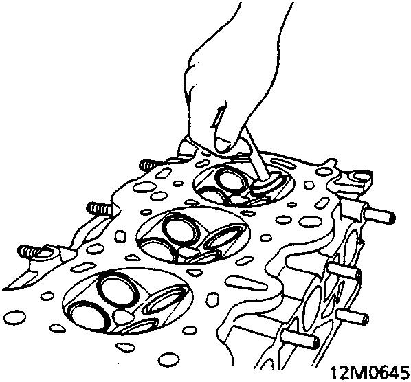 A hand using a valve seat cutter on a cylinder head