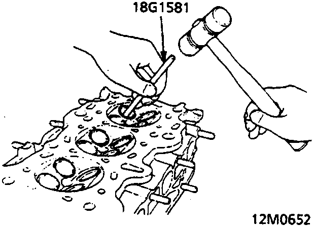 Diagram showing a tool being used to drive a valve guide out of the cylinder head with a hammer