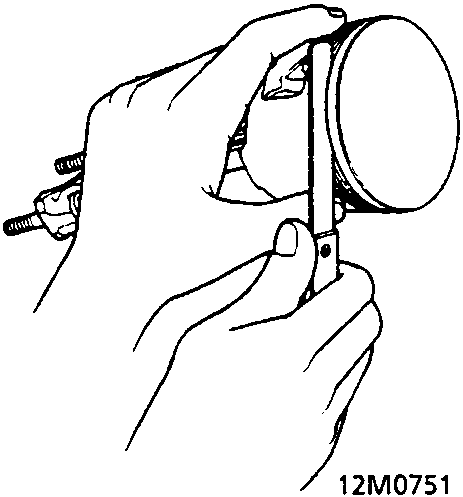Diagram showing hands using a feeler gauge to measure the clearance between a piston ring and its groove