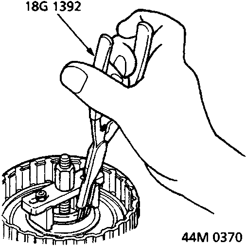 Diagram showing hands using tools to remove a snap ring from a clutch assembly